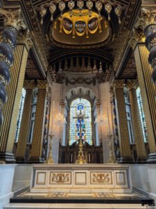 Interior photo of the high altar at St Paul’s Cathedral, showing gold detailing, tall columns, a stained‑glass window, and ornate Baroque architecture.