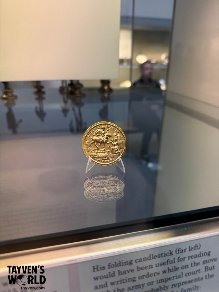 Gold Sovereign – Reverse Side (St George and the Dragon) Reverse side of a gold sovereign displayed in a museum case, showing a detailed design of St George on horseback slaying the dragon.