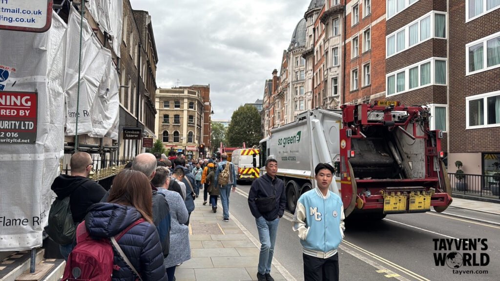 London Street Scene Near the Museum Busy London street with pedestrians walking past construction barriers and service vehicles.