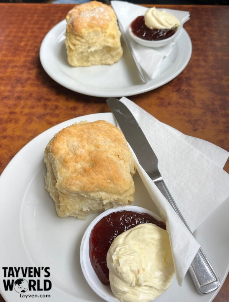 Classic British Scones Two plates of scones served with strawberry jam and clotted cream on a café table.