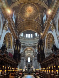 Interior photo of St Paul’s Cathedral showing the choir stalls, glowing individual lamps, ornate arches, and the richly decorated dome above.