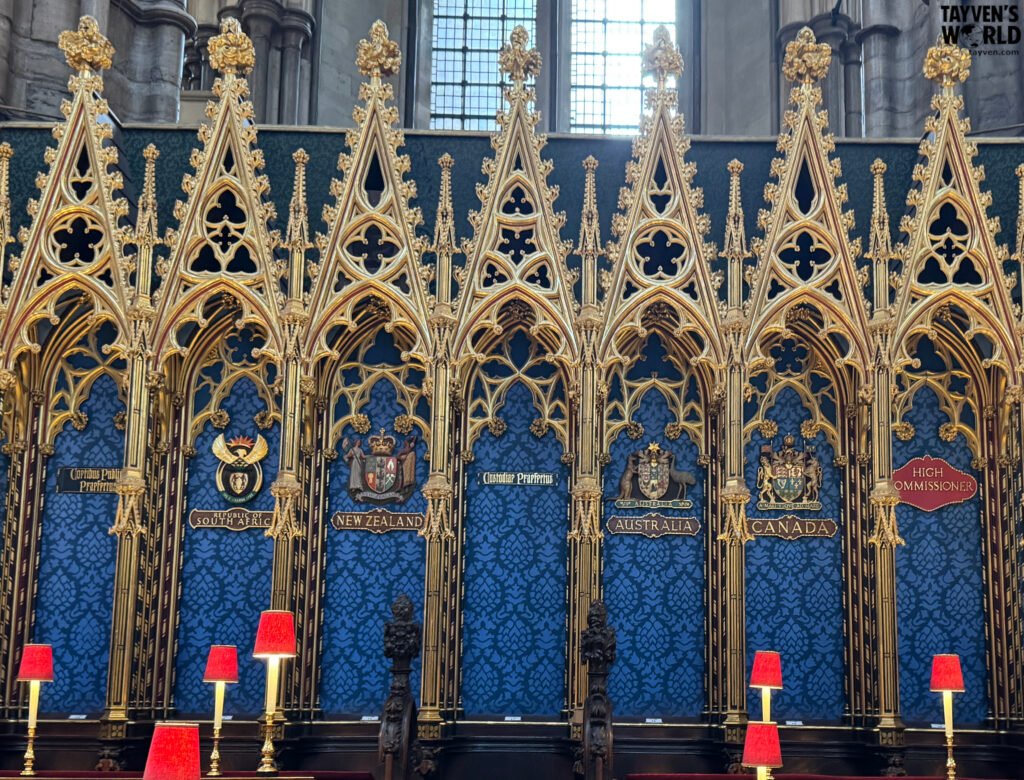 Ornate Gothic seating area inside Westminster Abbey displaying Commonwealth shields for Australia, New Zealand, Canada, and South Africa.