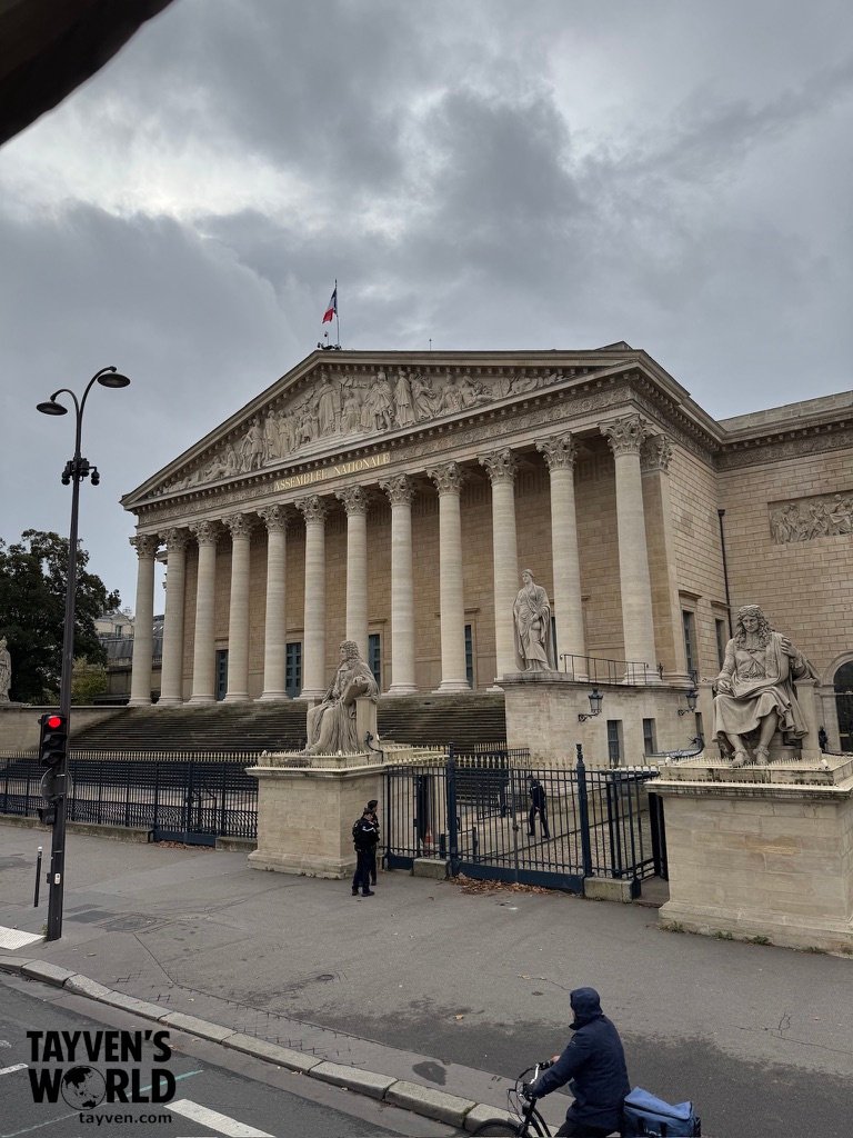 Front façade of the Palais Bourbon in Paris with Corinthian columns and statues under an overcast sky.