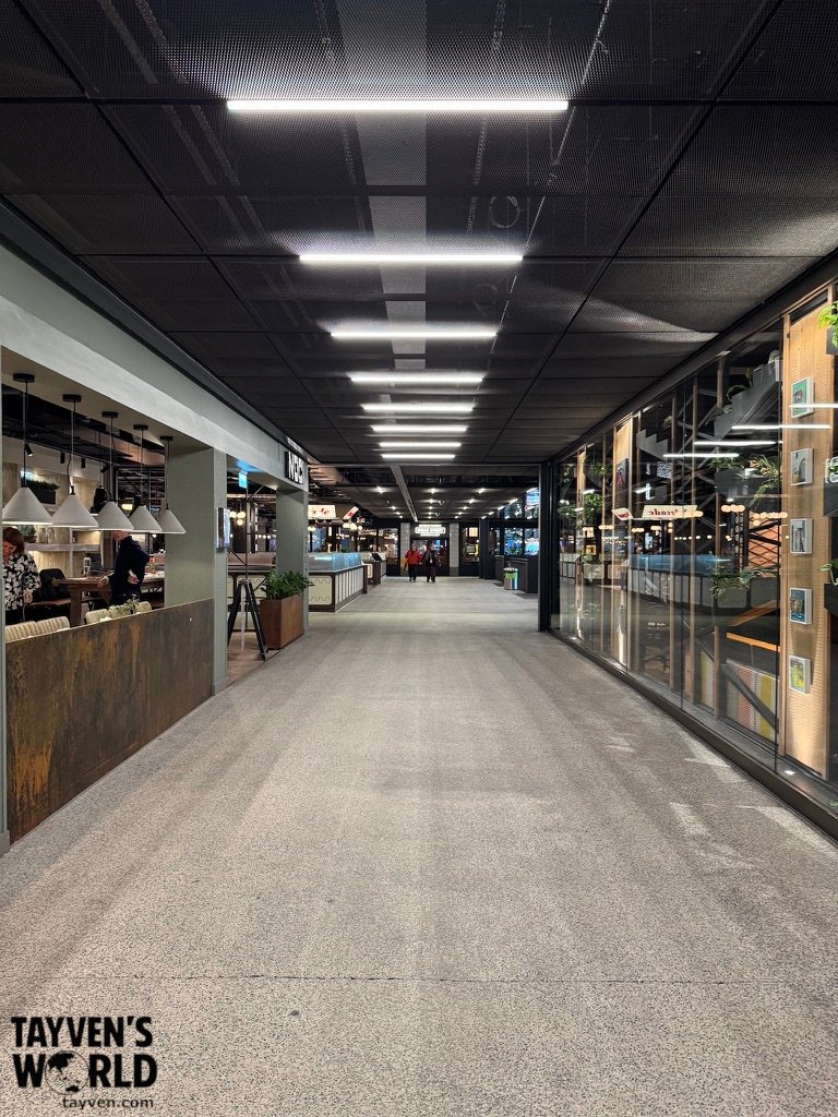 Modern indoor corridor at Battersea Power Station with restaurants, pendant lighting, and linear LED ceiling lights.