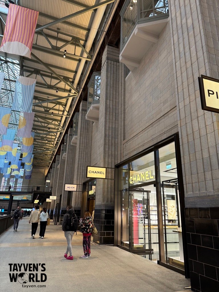 Interior of Battersea Power Station’s shopping mall with CHANEL storefront and colourful hanging banners.