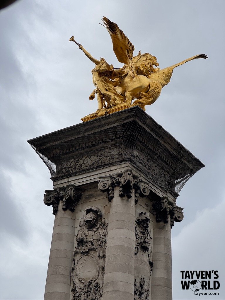 Gilded Pegasus statue atop a decorated stone column on Pont Alexandre III in Paris.