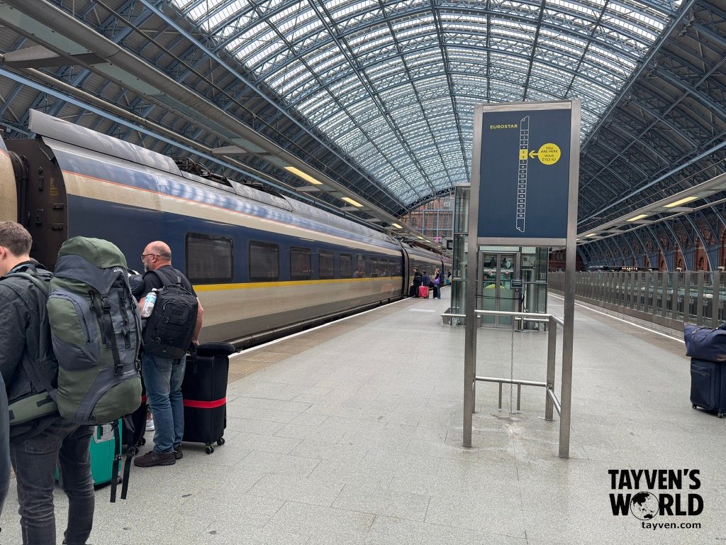 Eurostar train on platform under glass roof at St Pancras International with passengers boarding.
