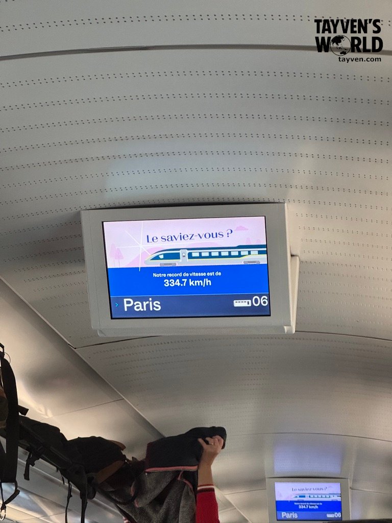 Digital display inside Eurostar train showing record speed of 334.7 km/h en route to Paris.