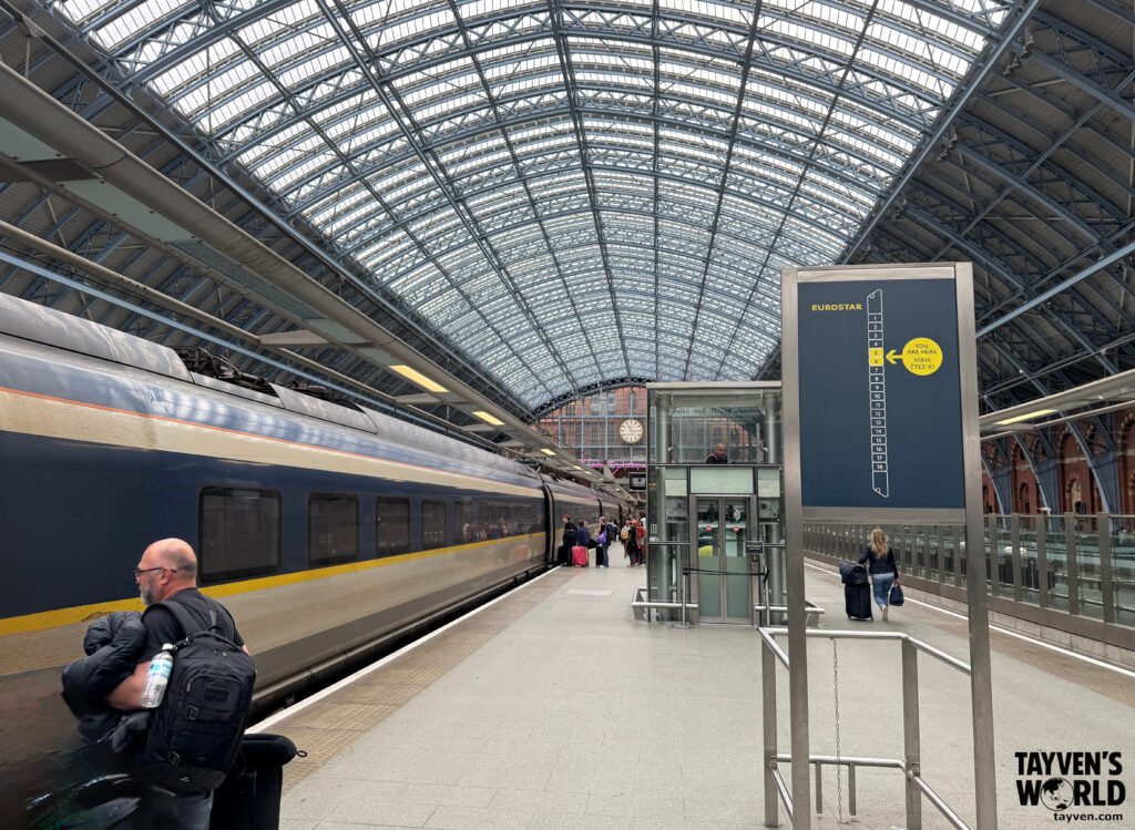 Eurostar train under glass roof at St Pancras with station clock and passengers.
