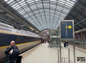 Eurostar train under glass roof at St Pancras with station clock and passengers.