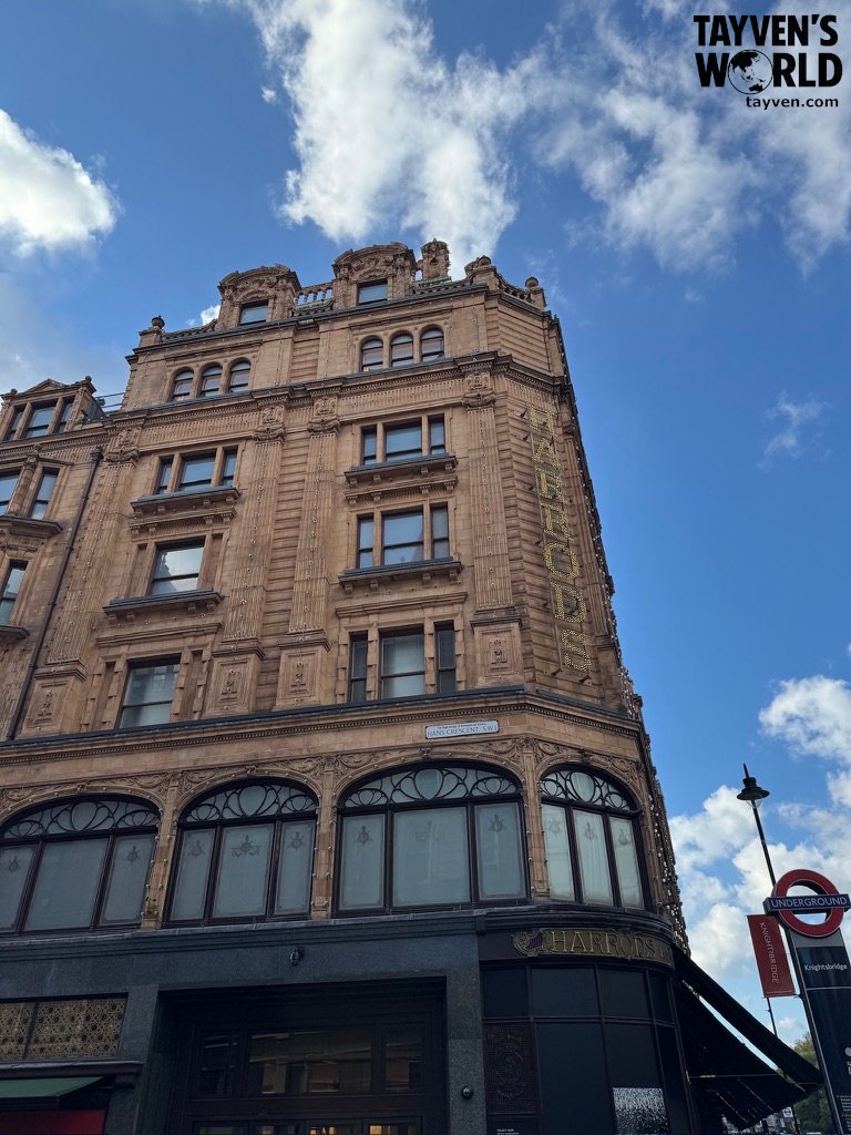 Exterior of Harrods department store in Knightsbridge under a bright blue sky.