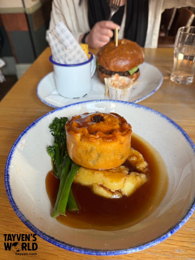 Traditional British pie with mashed potatoes and gravy served with broccolini at a London pub.