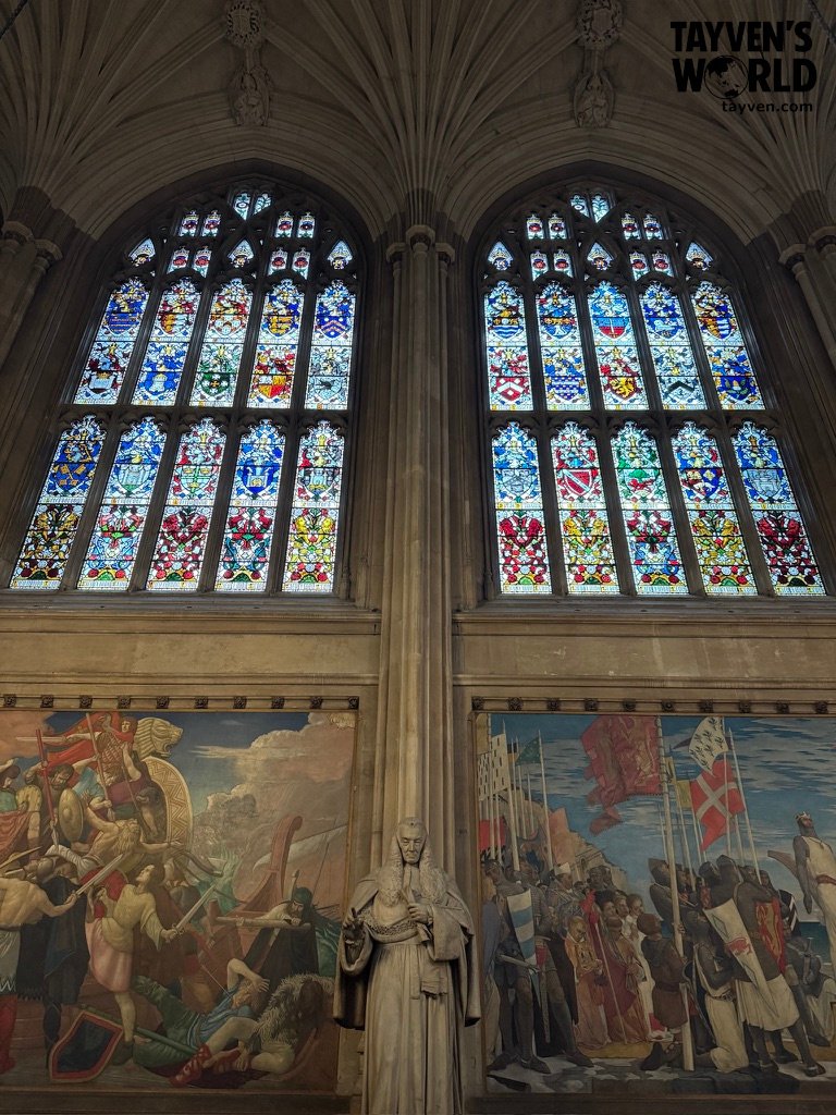 Stained glass windows and murals depicting historical scenes inside Westminster Hall.