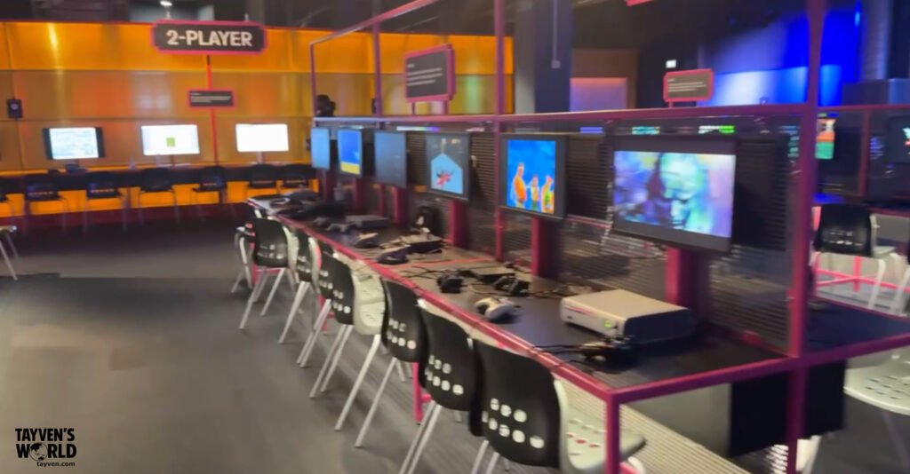 Interactive two‑player gaming stations with retro consoles and colorful screens at the Power Up exhibition in London.