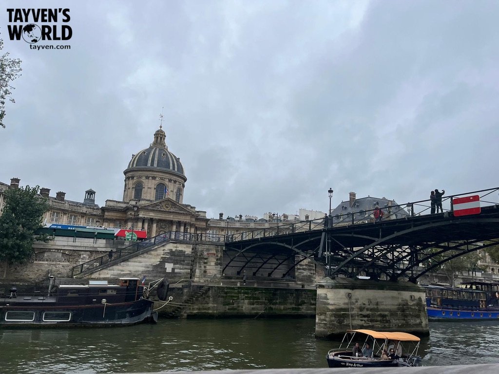 View of the Institut de France dome and pedestrian bridge crossing the Seine River in Paris.