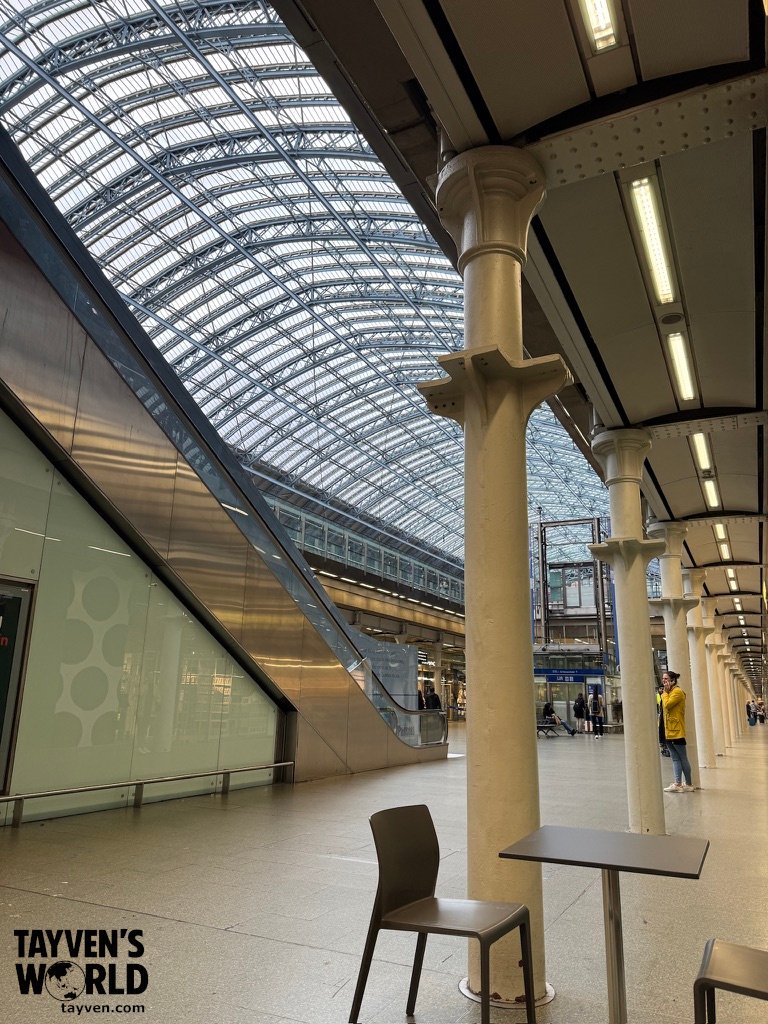 Glass and steel roof structure inside St Pancras International station with seating and columns.