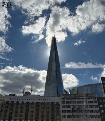 The Shard skyscraper towering above London Bridge Hospital with sunlight breaking through clouds.