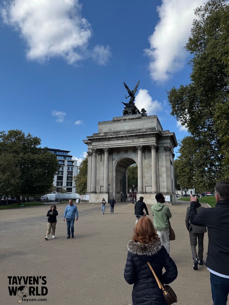 Wellington Arch in London with people walking beneath a blue sky.