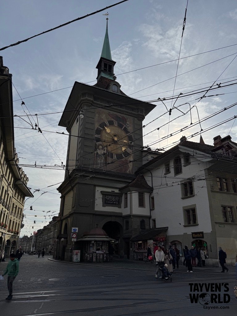 Medieval clock tower in Bern’s old town with tram wires overhead and pedestrians below.