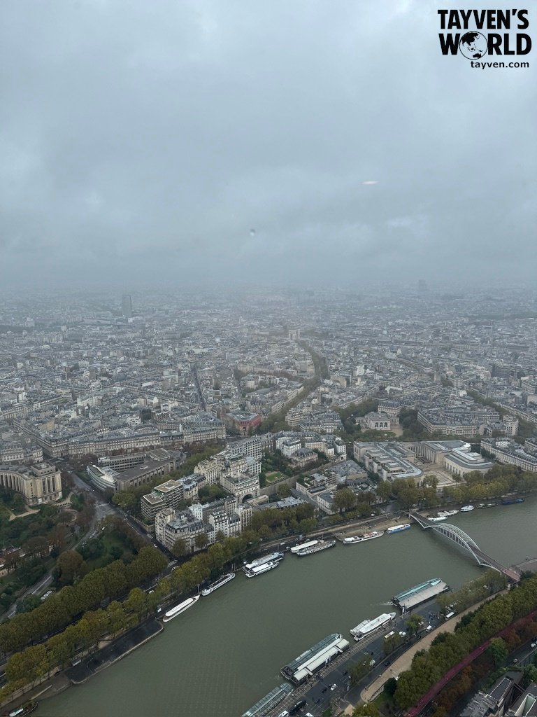Overcast view of Paris from the Eiffel Tower showing the Seine River and city layout.