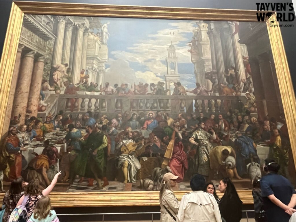 Visitors admiring a grand Renaissance banquet painting inside the Louvre Museum.