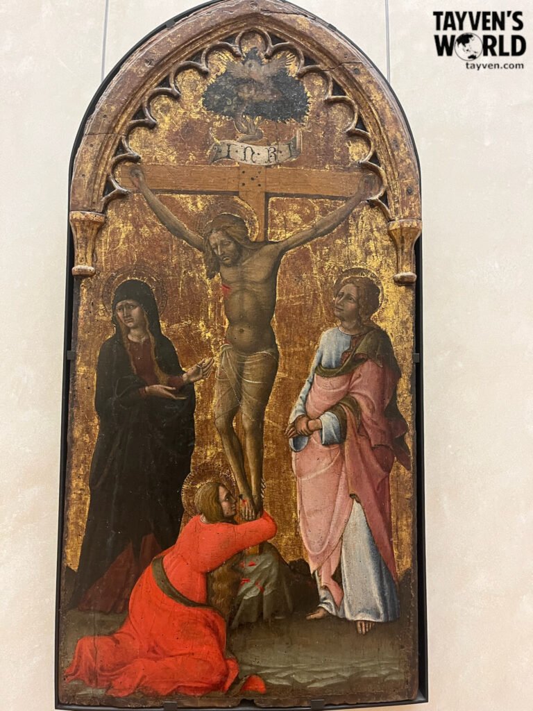 Medieval crucifixion painting on a gilded wooden panel displayed in the Louvre Museum.