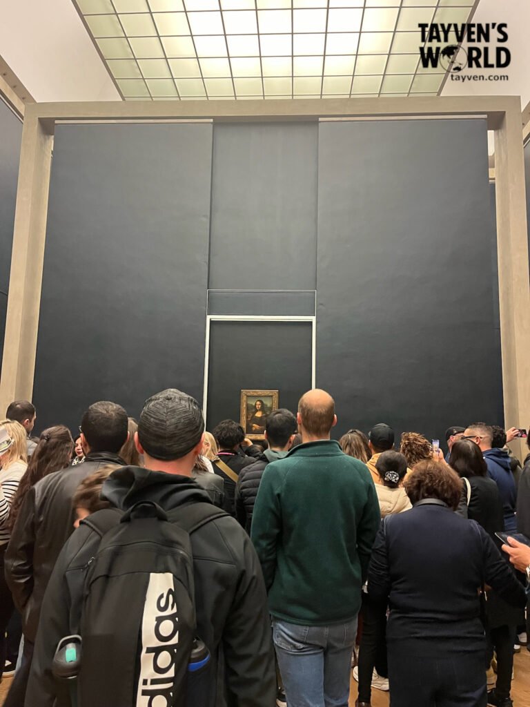 Visitors crowding around the Mona Lisa painting at the Louvre Museum.