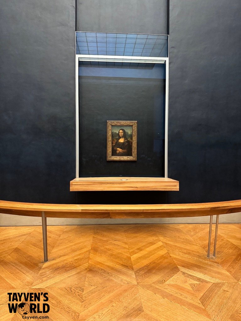 The Mona Lisa painting displayed behind glass at the Louvre Museum.
