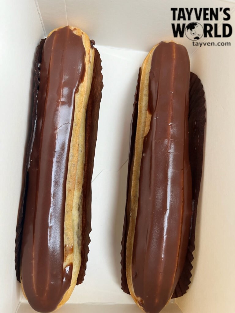 Two chocolate éclairs in a white box from a Paris bakery.