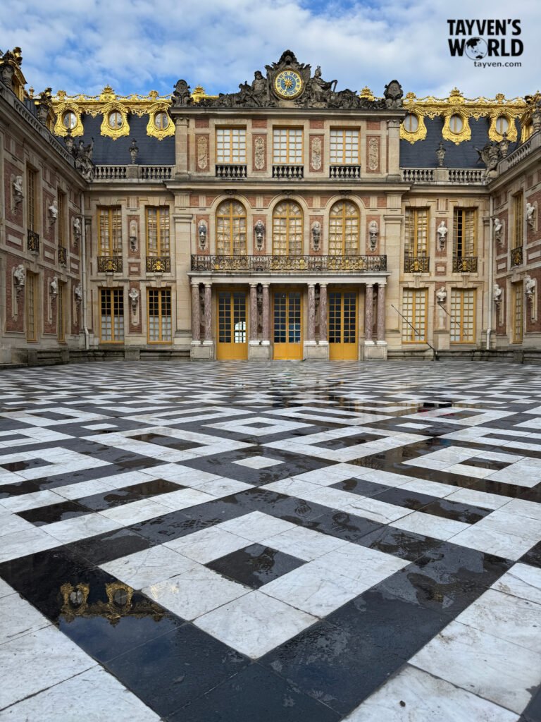 Black‑and‑white geometric marble floor in the main courtyard of Versailles.