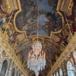 Ornate ceiling and chandeliers inside the Hall of Mirrors at Versailles.