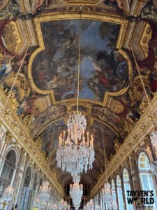 Ornate ceiling and chandeliers inside the Hall of Mirrors at Versailles.