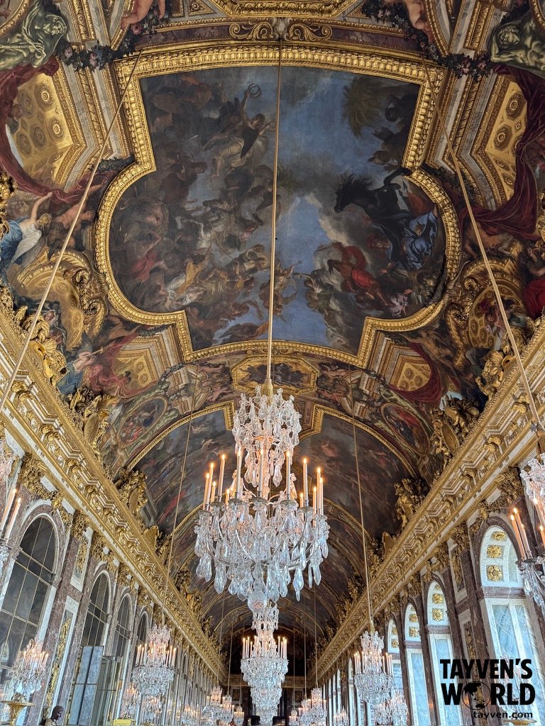 Ornate ceiling and chandeliers inside the Hall of Mirrors at Versailles.