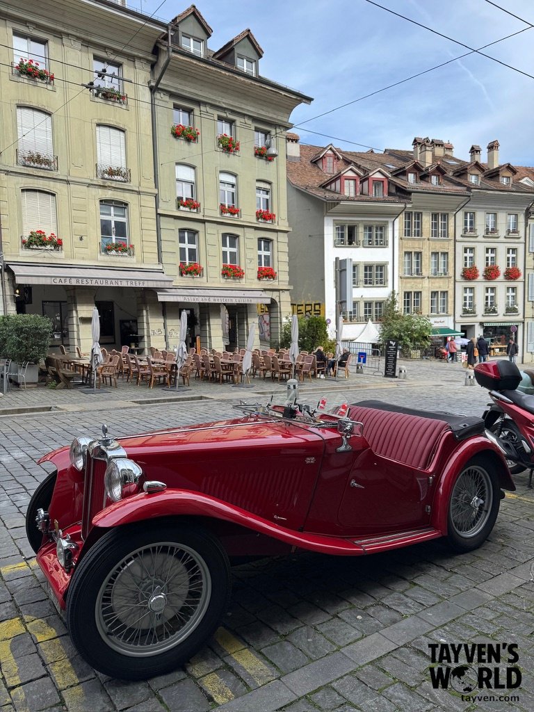 Vintage red convertible parked on cobblestone street in Bern