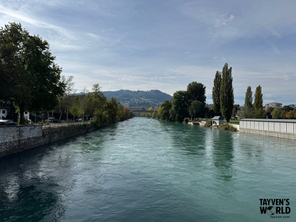 Calm river in Bern with trees and hills in the background