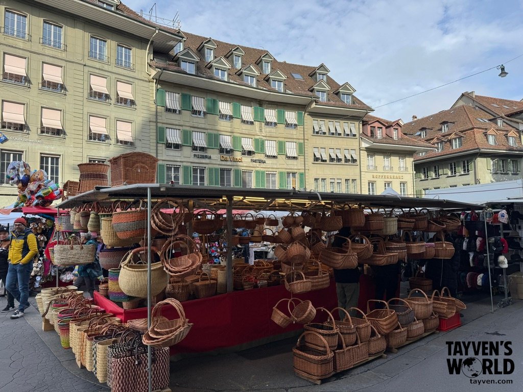 Outdoor market stall in Bern selling woven baskets under historic buildings