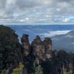 The Three Sisters rock formation rising above forested valley in the Blue Mountains.