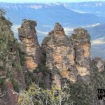 The Three Sisters rock formation rising above forested valley in the Blue Mountains.