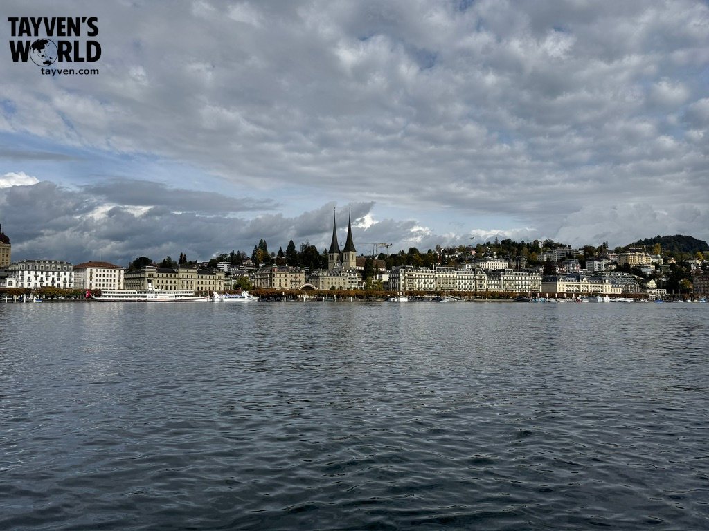 View of Lucerne’s lakeside skyline with twin church spires and historic buildings reflected in the water.