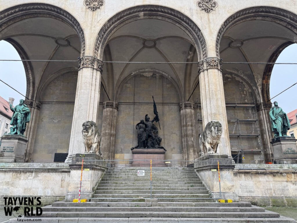Stone lions, bronze statues and arched monument at Munich’s Feldherrnhalle