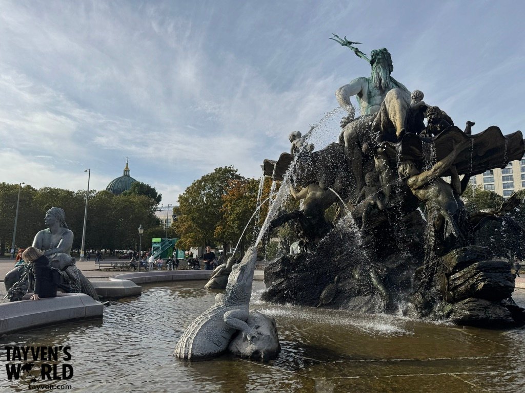 Neptune Fountain with bronze figures, water jets and Berlin architecture behind it