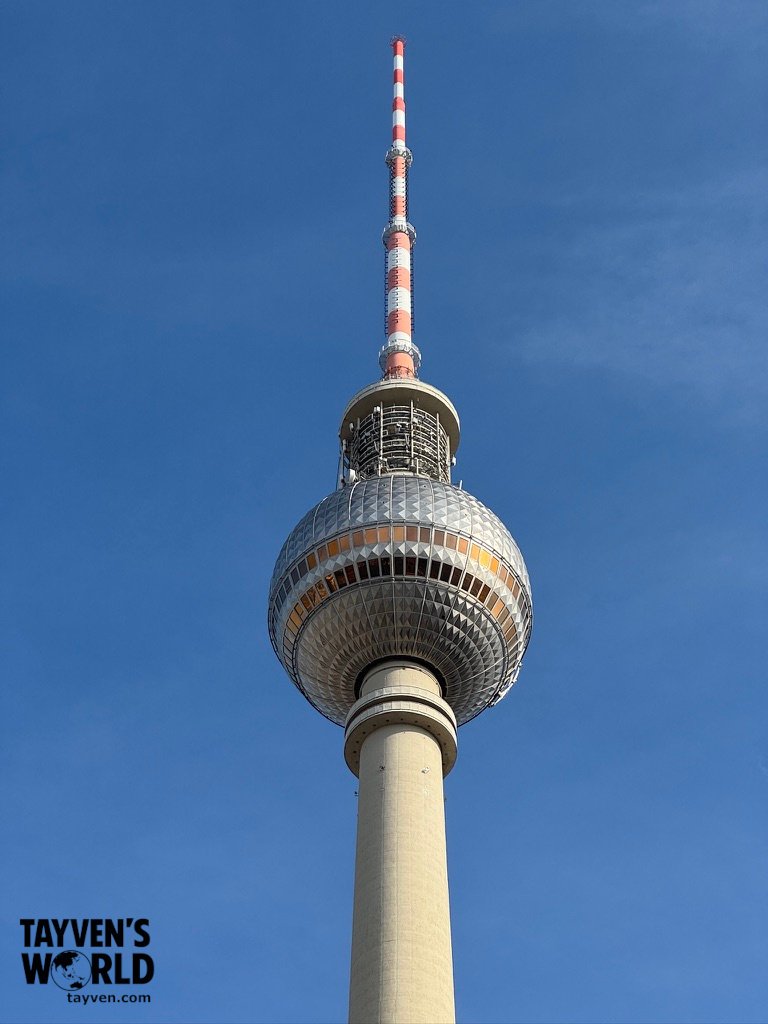 Close-up view of the Berlin TV Tower observation sphere and antenna against a blue sky