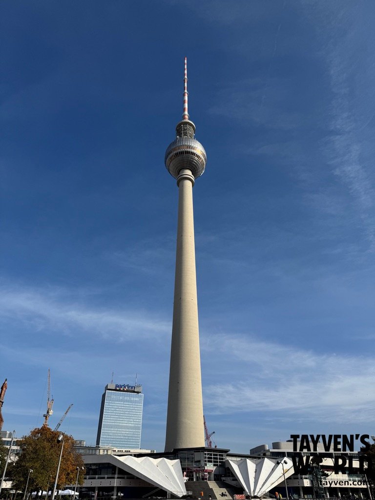 Full view of the Berlin TV Tower rising above Alexanderplatz under a blue sky