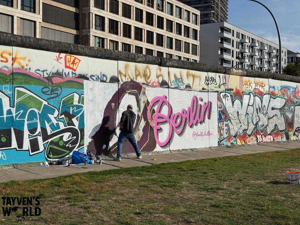 Artist painting a mural on the East Side Gallery section of the Berlin Wall