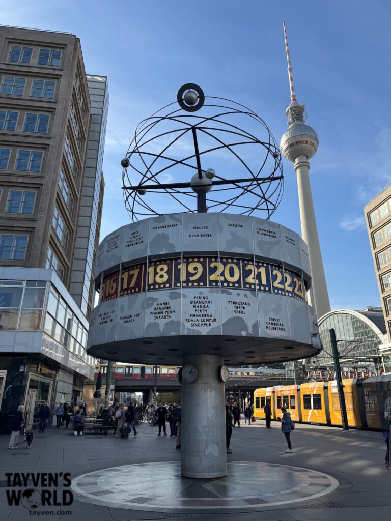 World Clock at Alexanderplatz with the Berlin TV Tower and passing trams behind it