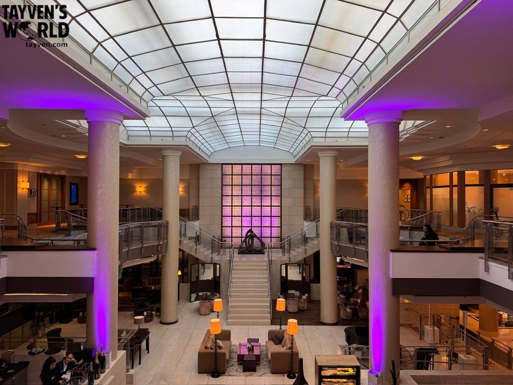 Spacious Hilton Berlin lobby with columns, central staircase and purple lighting